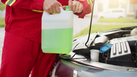 service worker man pours car fluid windscreen green cleaning washer glass summer or winter cleaner