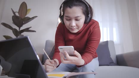 Businesswoman-redshirt-using-a-tablet-with-headphone-for-meeting-online-at-home