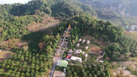 Luftdrohne-Eines-Einzigartigen-Tempels-Mit-Einem-Goldenen-Buddha-Auf-Einem-Berg,-Umgeben-Von-Kokospalmen-In-Ao-Nang-Krabi,-Thailand