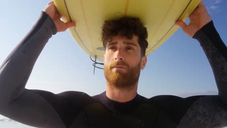 surfista masculino llevando una tabla de surf en su cabeza en la playa 4k