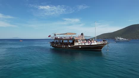 drone of boat arriving in bay of crystal blue waters on the turkish riviera in bodrum