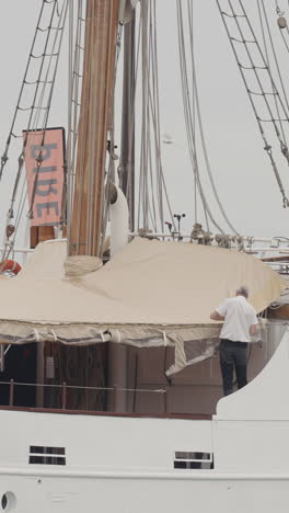 sailor repairing a sail cover on a ship