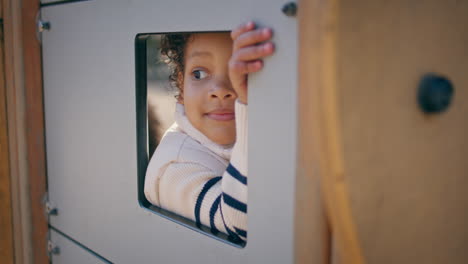 niño rizado jugando en una casa de juguetes de cerca. chica linda mirando por la ventana