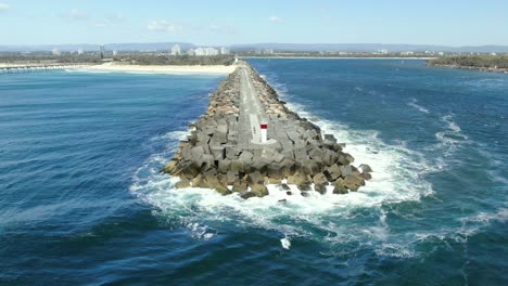 Fliegen-Um-Die-äußerste-Spitze-Des-Gold-Coast-Seaway-Mit-Kleinen-Wellen,-Die-Auf-Die-Felsen-Schlagen