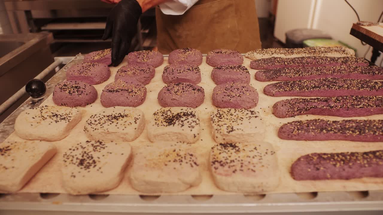 Bakery chef making different various of fresh Artesian buns and baguettes using traditional recipe close-up. Young man kneading dough. Artisan bread is making by skill bakers using natural and high-quality ingredients. Food with health and flavour benefits. Bakery shop and market