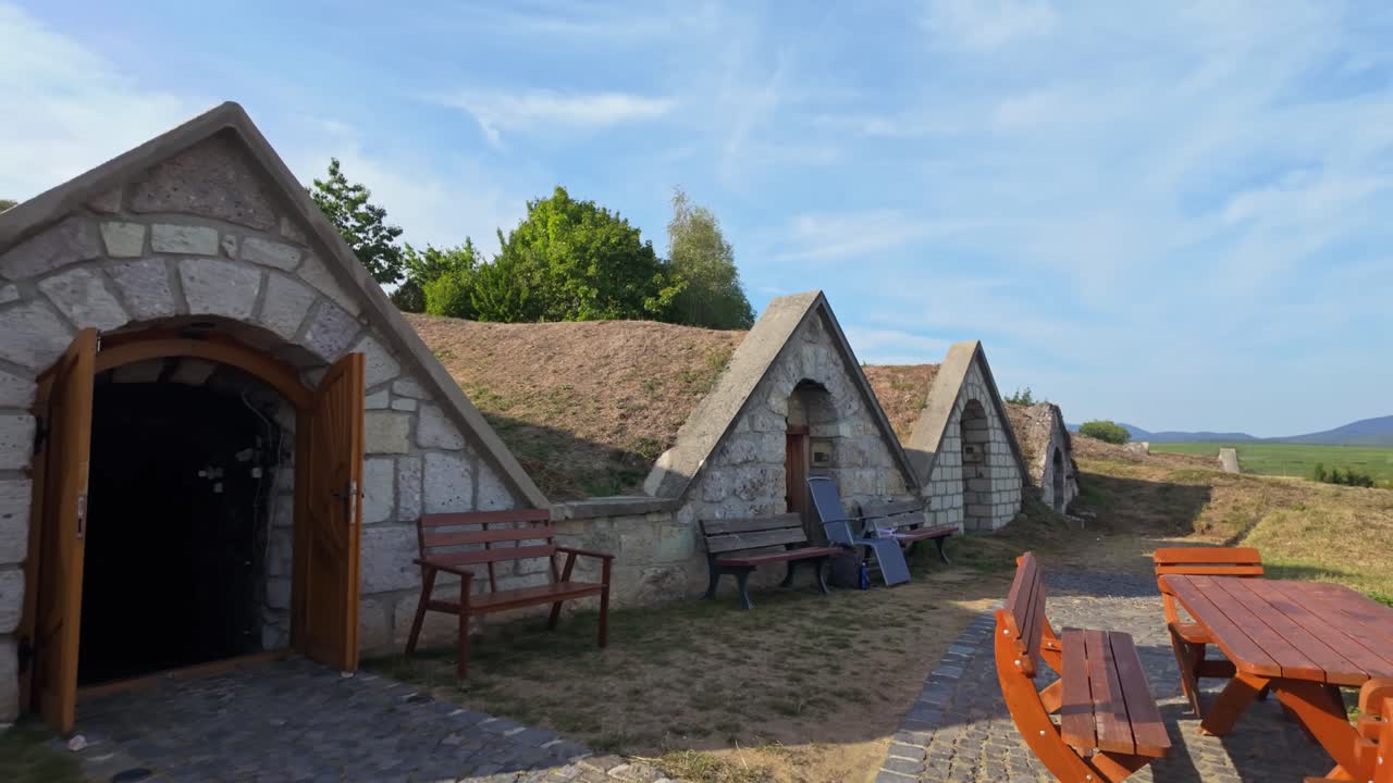 Open winery cellar with outdoor tables and benches waiting for guests at Kőporosi Pincesor, Hercegkút, Hungary