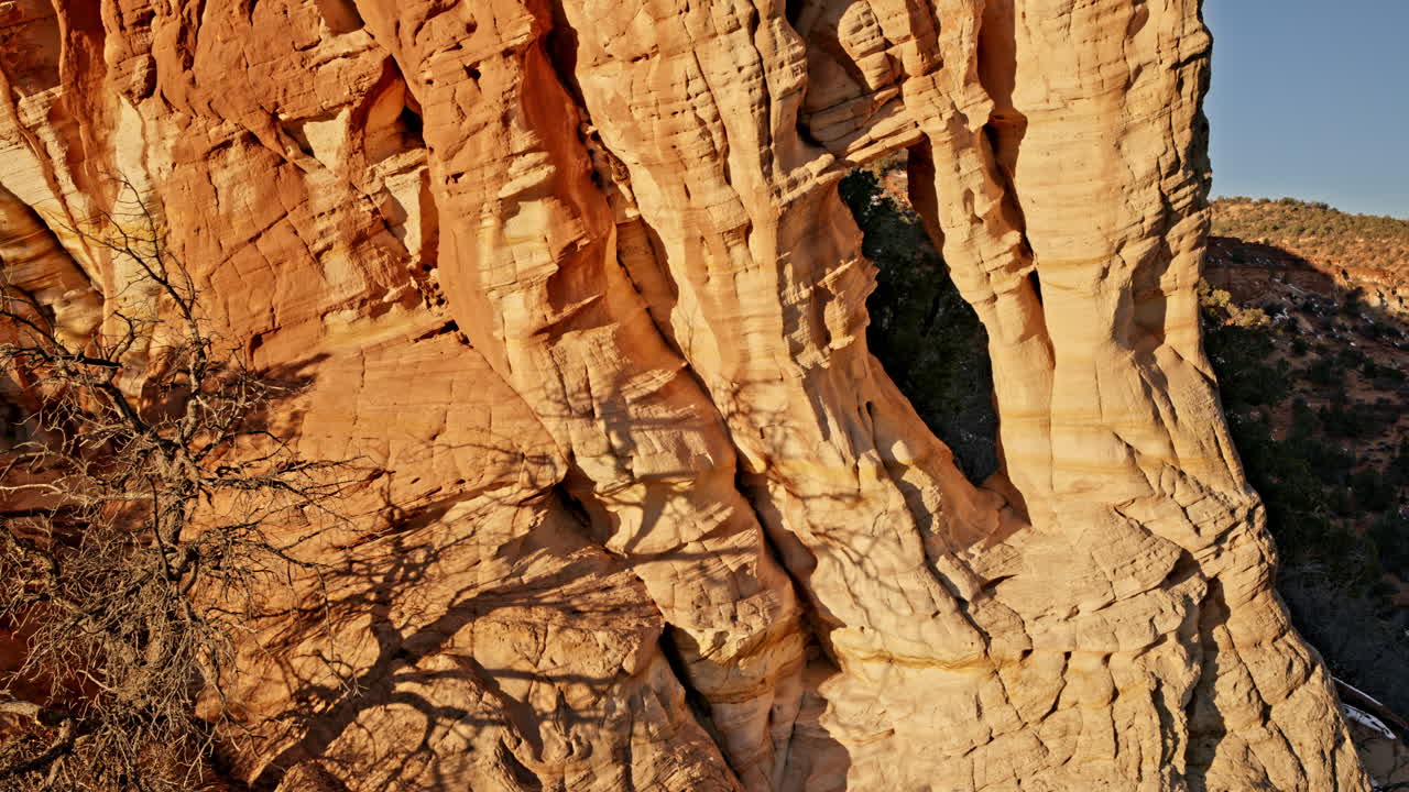 Serene drone shot floating over a tucked-away desert arch as the sun rises near Kanab, Utah.
