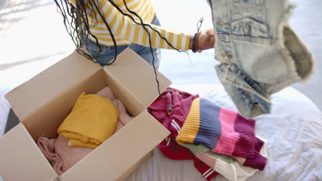 packing clothes into cardboard box, woman organizing wardrobe at home