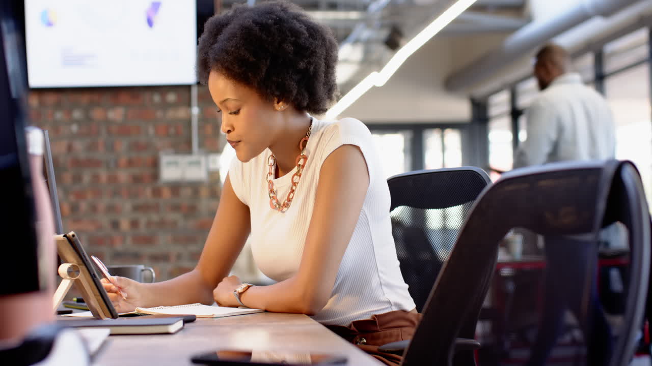 African American businesswoman writing notes at her desk in modern office