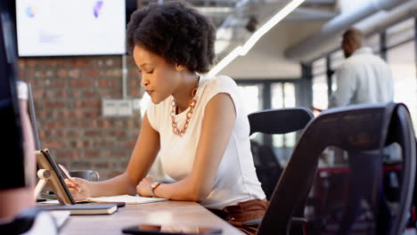 african american businesswoman writing notes at her desk in modern office