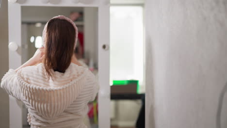 lady listens to music doing cosmetic mask after washing. woman with fabric face mask rejoices at end of work week dancing near mirror in bath area