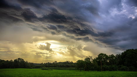 Glowing-sunshine-and-dark-summer-thunder-clouds-flow-above-agriculture-landscape