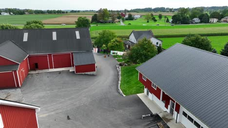 american farm with red barns, washline, farmhouse and rural countryside with fields and trees