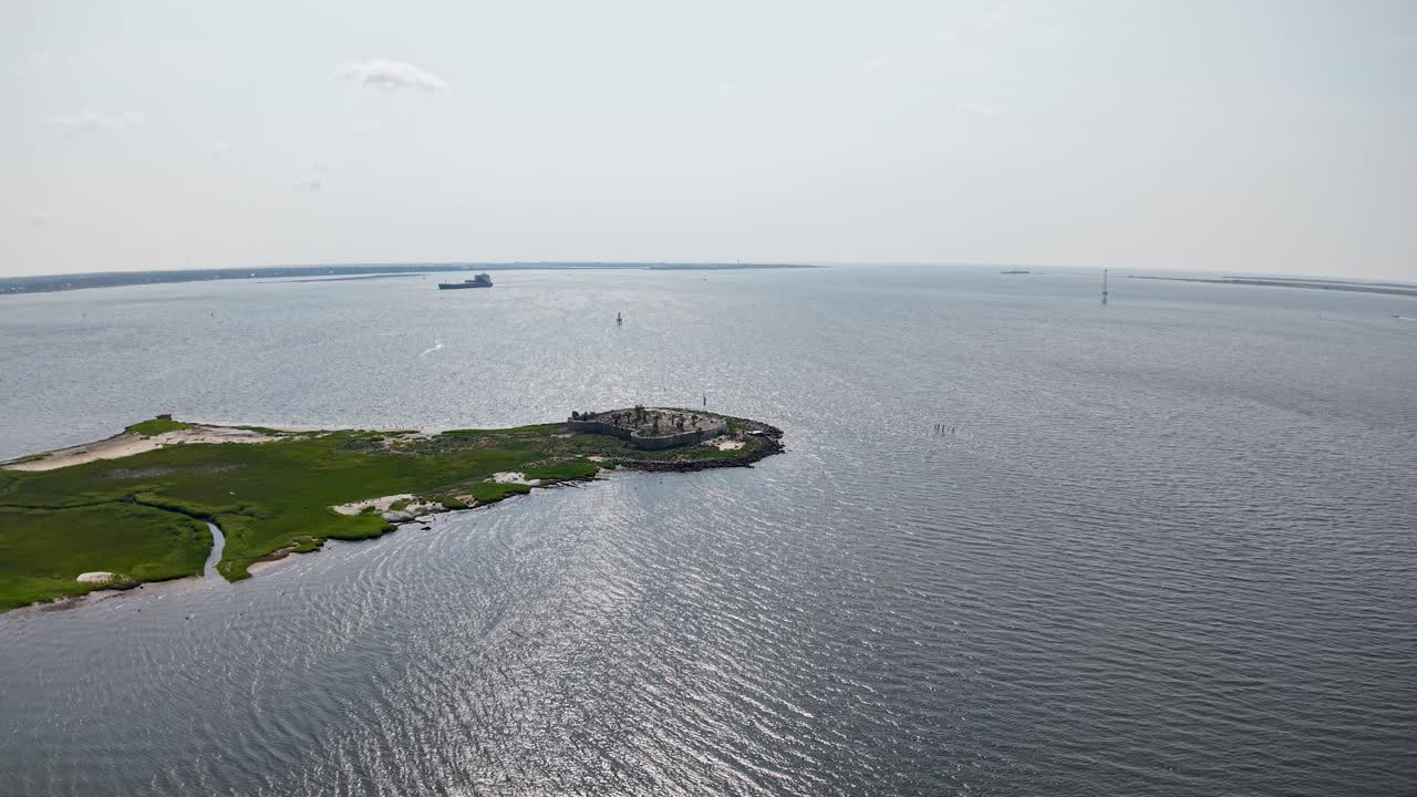 Aerial footage shows a small dock and green island in the calm waters of Charleston Harbor, with boats and ships visible on the horizon