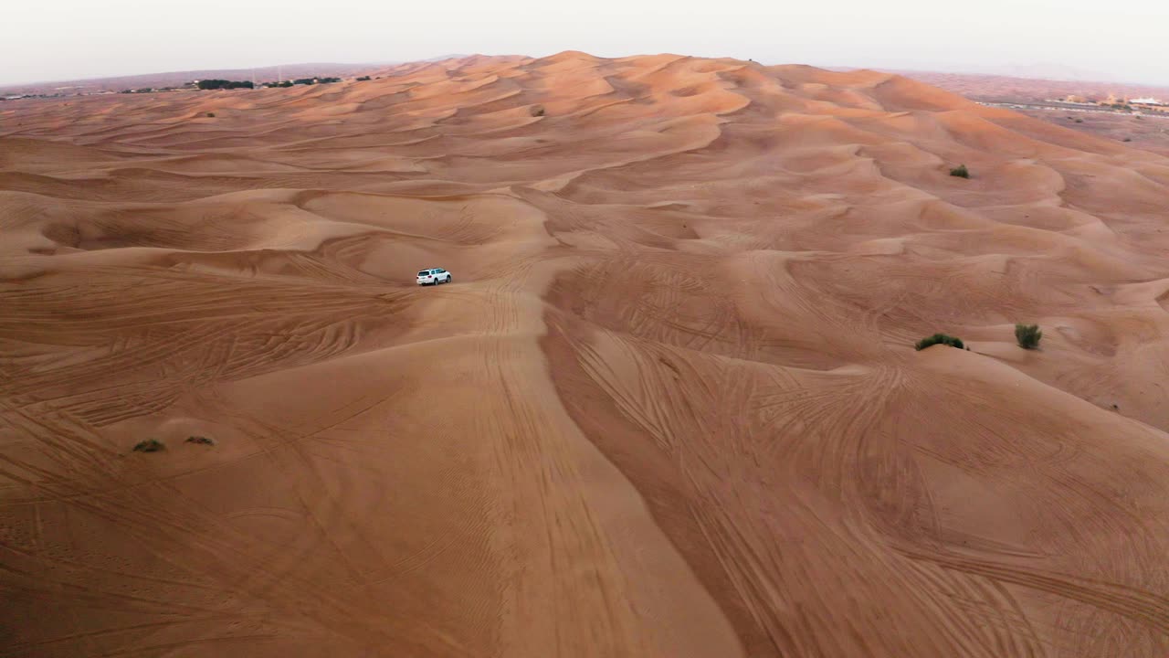 toma aérea de un camión 4x4 blanco en la arena del desierto