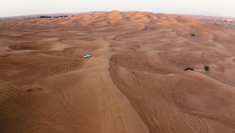 Aerial-Drone-Shot-Of-A-White-4x4-Car-In-The-Desert-Sand