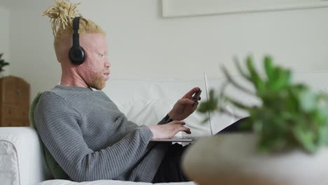 hombre albino afroamericano con rastas usando tableta y auriculares