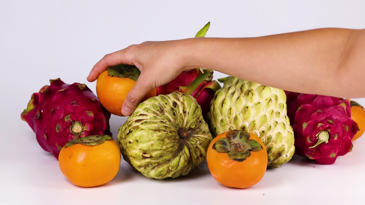Una mano selecciona fruta de una colorida exhibición