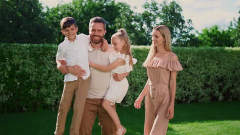 father holding daughter and son on hands. parents and kids posing at camera