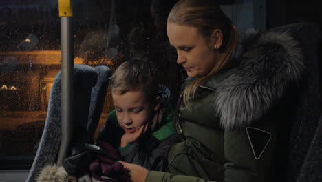 niño con madre usando teléfono celular en el autobús