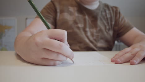 a young boy writing on paper with a pencil