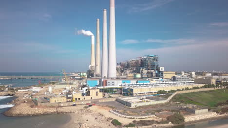 Aerial-shot-approaching-the-Hadera-Desalination-Plant,-Israel,-over-the-beach-and-water