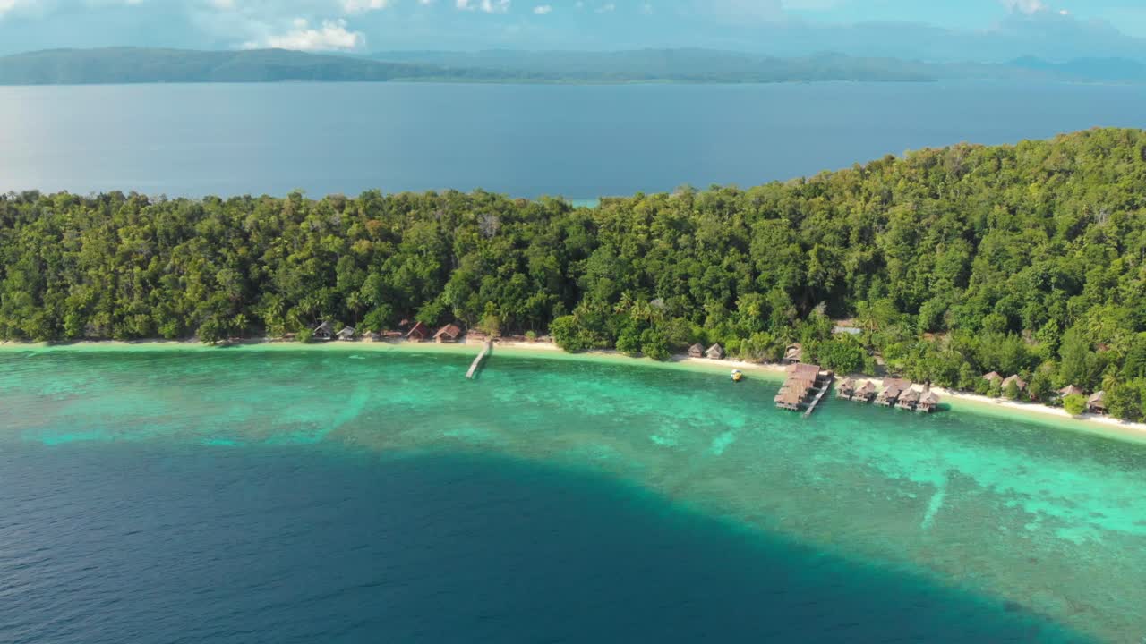 vista aérea de la isla de kri en raja ampat, indonesia, mostrando su exuberante vegetación, aguas turquesas y bungalows sobre el agua