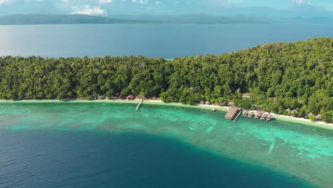 Aerial-view-of-Kri-Island-in-Raja-Ampat,-Indonesia,-showcasing-its-lush-greenery,-turquoise-waters,-and-overwater-bungalows