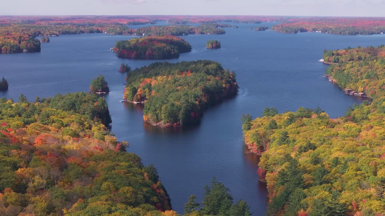 Colorful autumn forest surrounding calm blue lakes and islands, aerial view