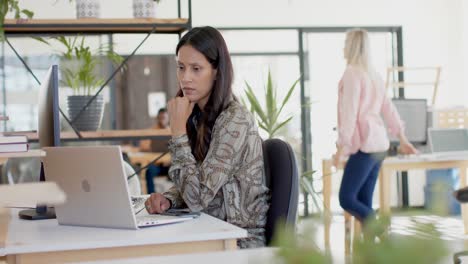 Busy-biracial-businesswoman-using-laptop-at-table-in-slow-motion