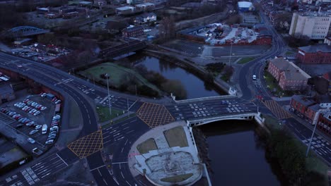 aerial view looking down city centre canal roundabout infrastructure suburban streets traffic at daybreak slow left orbit shot