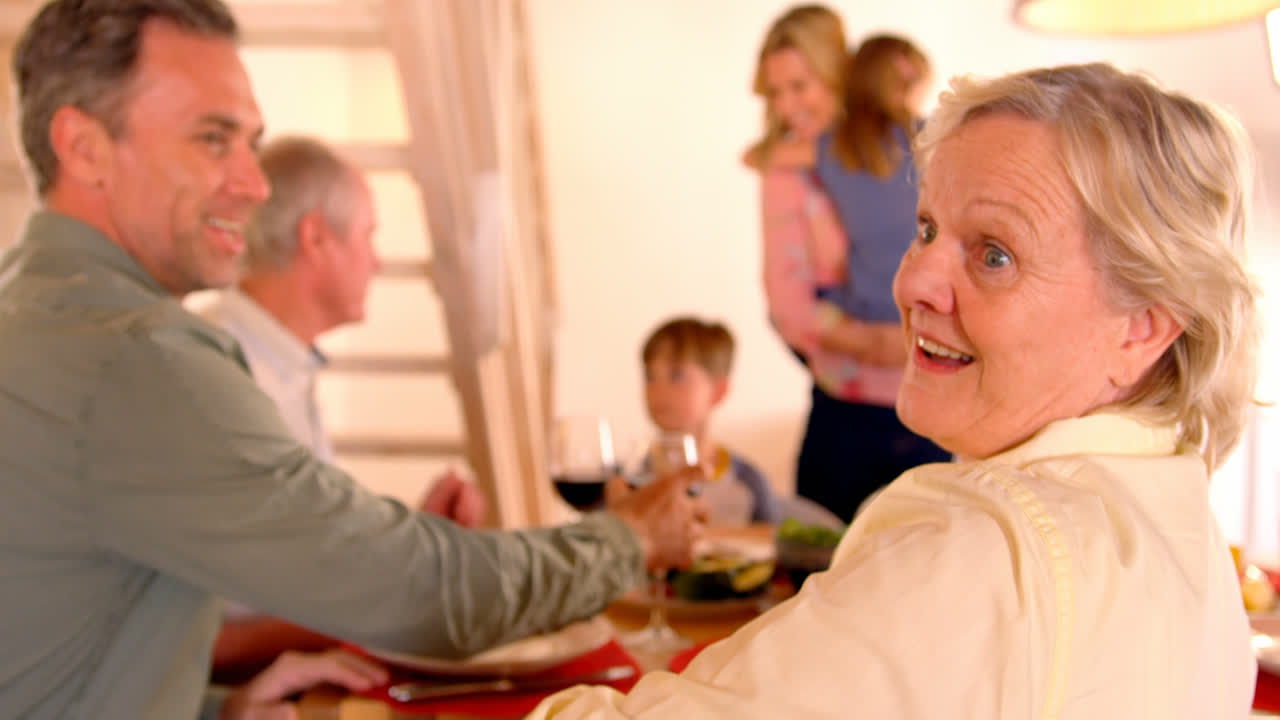 familia caucásica de varias generaciones comiendo comida juntos en la mesa del comedor en un hogar cómodo 4k