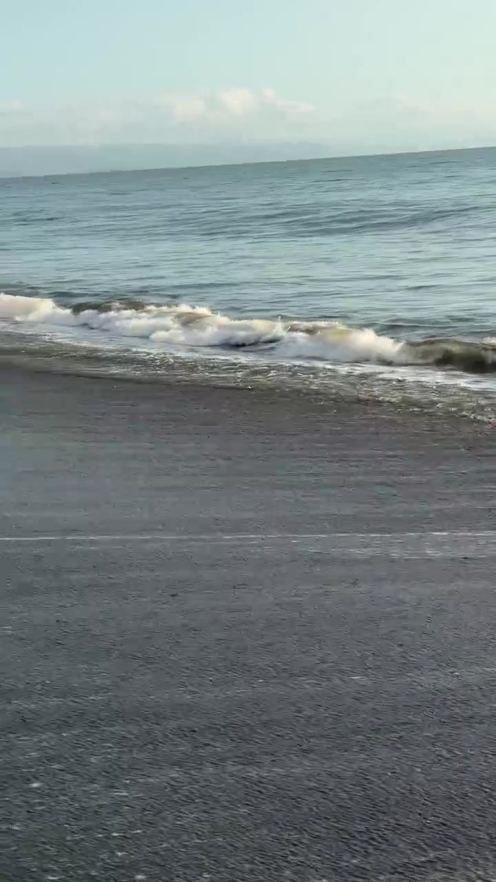 Dolci onde dell'oceano che si infrangono su una spiaggia di sabbia scura.