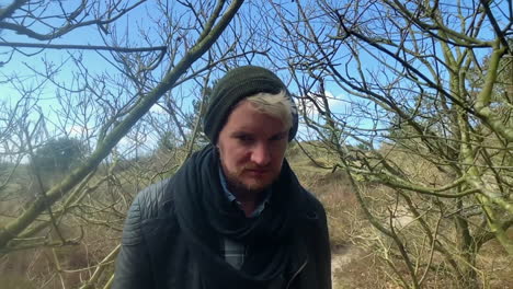 extreme slow motion shot of authentic hipster man with beard walking through the woods while looking straight into the camera