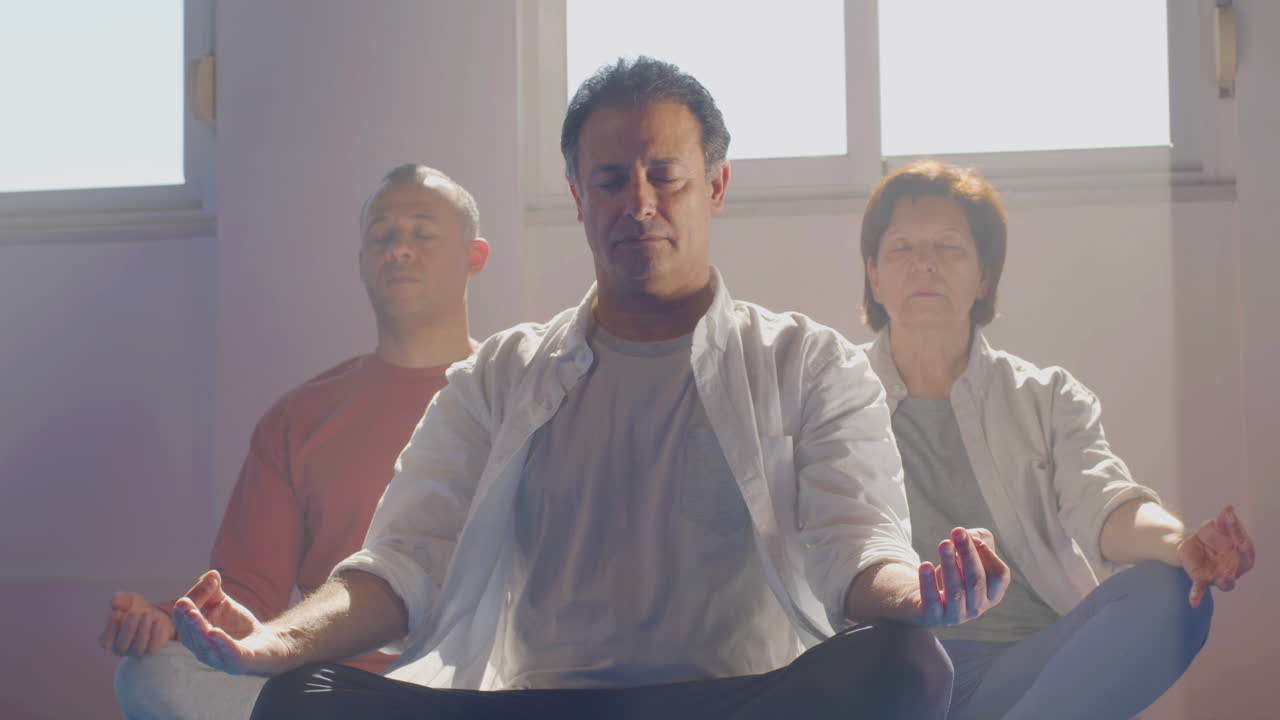 grupo de personas mayores meditando en posición de loto en el interior