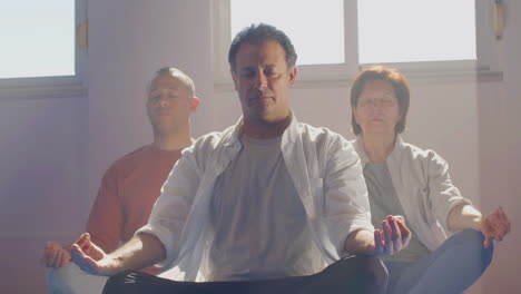 group of senior people meditating in lotus position indoor