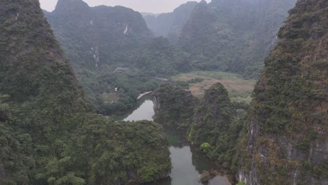 breathtaking aerial footage of lush vietnamese landscape, featuring verdant mountains, serene river, and tranquil atmosphere, shot in soft natural light highlighting rugged terrain