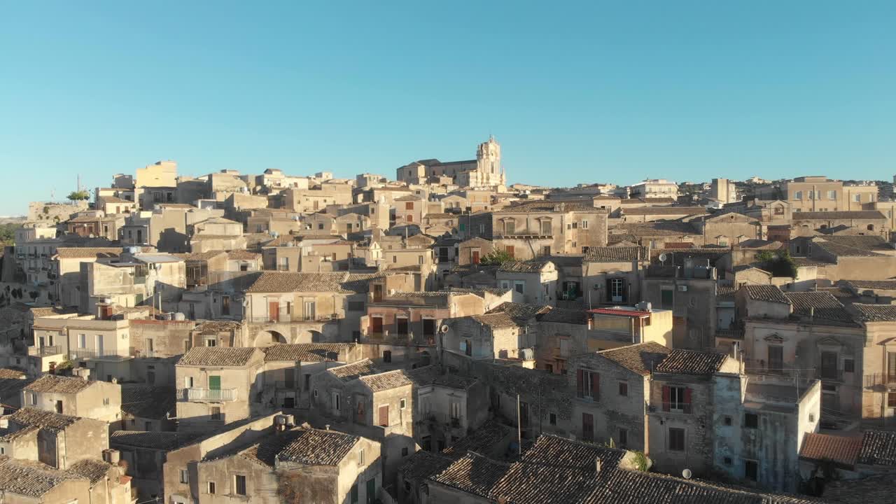 Sorvolo a bassa quota sulla città barocca di Modica durante l'alba e cielo azzurro, ripresa aerea.