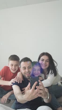 a man is taking a selfie with his family while sitting on a couch a happy man sitting on a couch smiles while taking a selfie with his family they share a joyful moment together