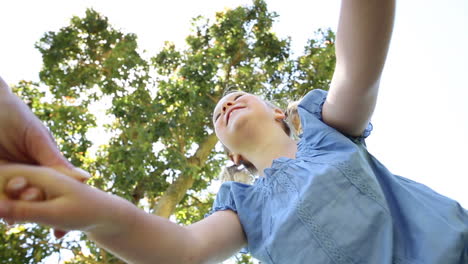 una niña feliz girando con su madre en el parque