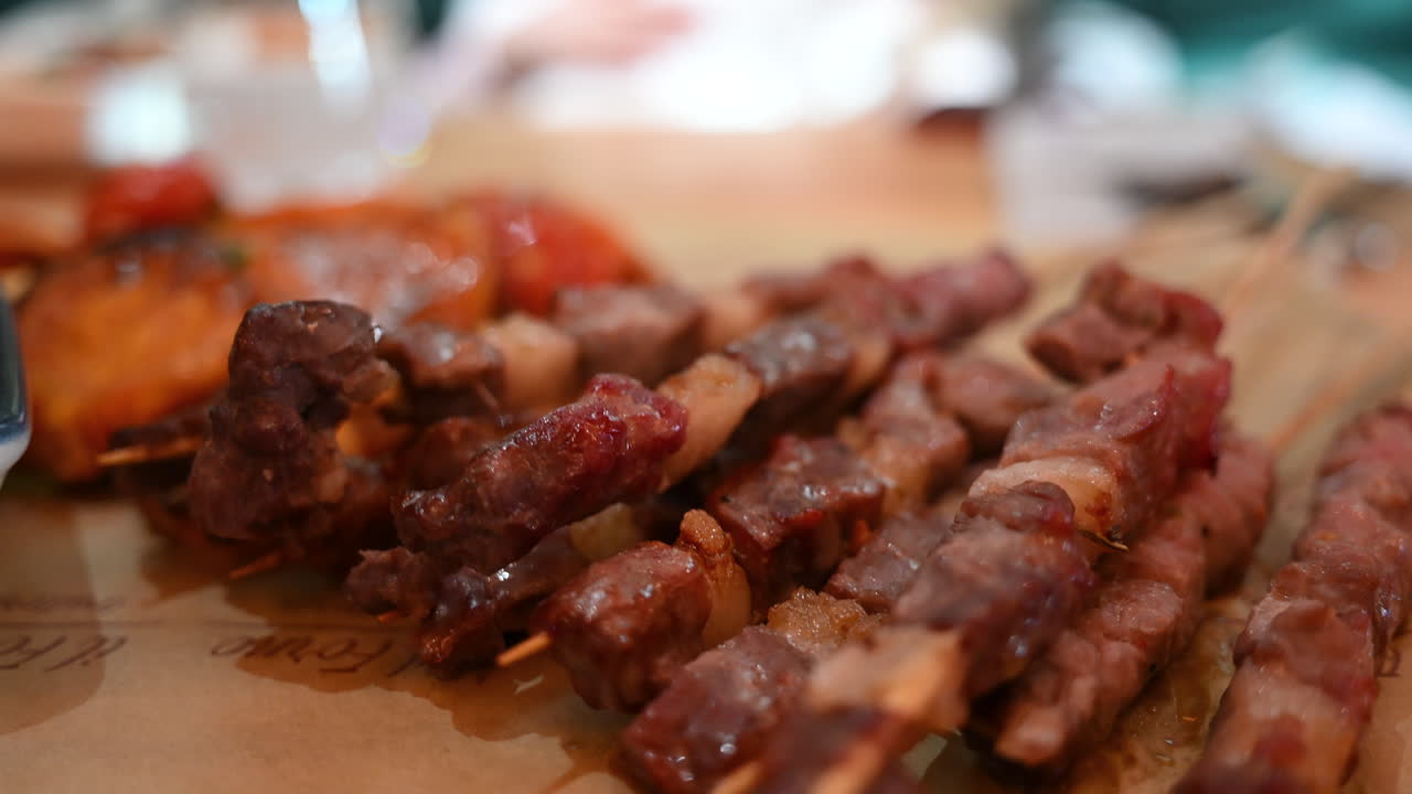 Vista dettagliata di spiedini di carne alla griglia su bastoncini di legno con profondità di campo ridotta