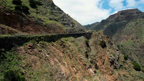 La-Gomera-Island,-Spain:-An-aerial-view-of-a-curvy-road-winding-through-tall-mountain-peaks,-Spain