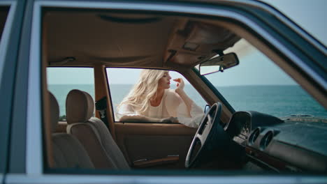 mujer en coche de época junto al océano