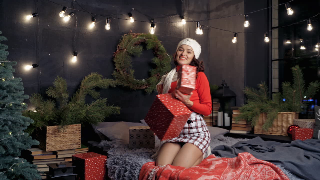 Pretty lady in white hat and red sweater received many presents on holidays. Happy woman with gift boxes. New Year celebration.