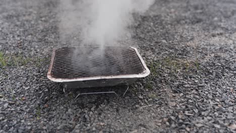 Gießen-Sie-Wasser-Auf-Einen-Einweggrill,-Um-Das-Glühen-Der-Kohle-Zu-Löschen-Und-Den-Grill-Zu-Löschen