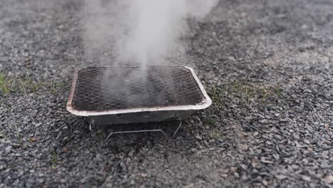 pouring water on a disposable barbecue to put out the glow from the coal and extinguish the grill