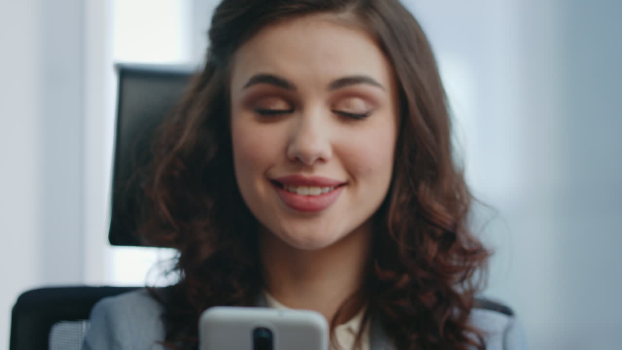 gerente sonriente mirando la pantalla de su teléfono inteligente en el lugar de trabajo leyendo un mensaje de cerca.