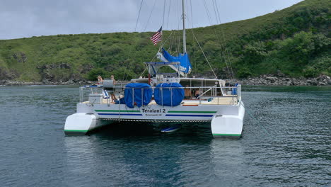 two girls grilling out and waving on the back of teralani two in honolua bay, maui hawaii