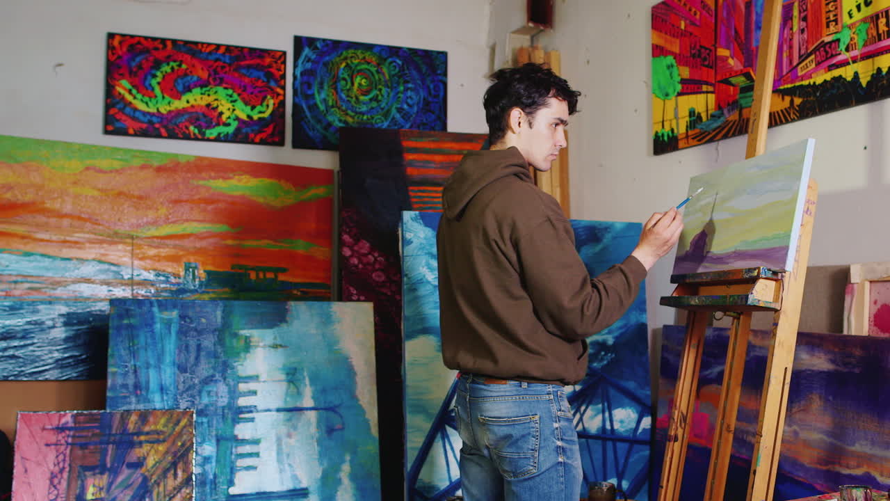 화가의 창작 스튜디오에서 일하는 젊은 혼혈 예술가가 그림을 그립니다.