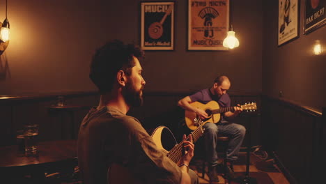 two musicians performing acoustic guitar music in a warm-lighted bar
